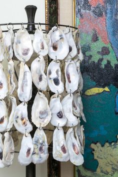 several oysters hanging from a metal rack in front of a wall with paintings on it