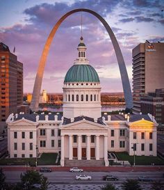 the capital building in st louis, missouri is lit up at dusk with the gateway arch visible