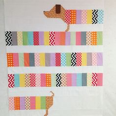 a quilted wall hanging with a dog on it's side and colorful strips in the background