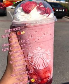 a hand holding a starbucks drink with strawberries and whipped cream