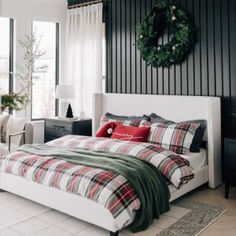 a bedroom decorated for christmas with plaid bedding and wreath on the wall above the bed