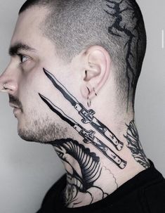 a man with tattoos on his face and neck holding scissors in front of his head