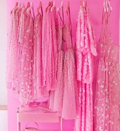 pink dresses are hanging up in a room