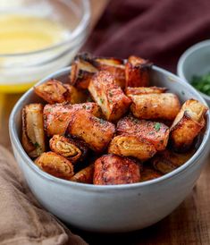 a white bowl filled with fried potatoes on top of a wooden table