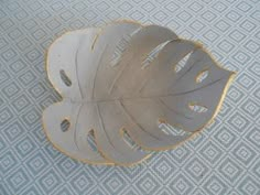 a white and gold leaf shaped object sitting on top of a blue carpeted floor