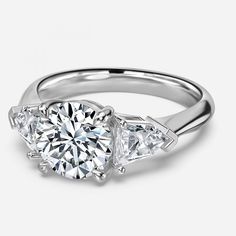 three stone engagement ring with side stones in 18k white gold, featuring an oval brilliant cut diamond and tapered baguets