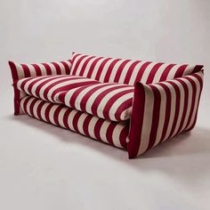 a red and white striped couch sitting on top of a white floor next to a wall