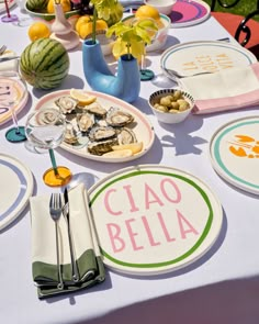 the table is set with plates, silverware and watermelon