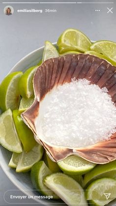 a bowl filled with sea salt and limes on top of a table next to a cell phone