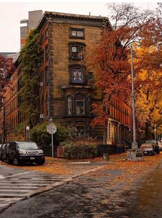 an old brick building with lots of windows on the corner in front of some parked cars