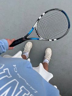 a person is holding a tennis racket in their hand while sitting on the ground