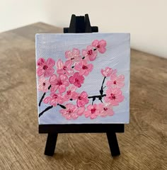 a small easel with a painting of pink flowers on it