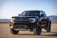 a black truck parked on top of a dirt field