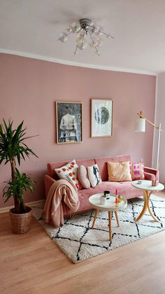 a living room with pink walls and pictures on the wall