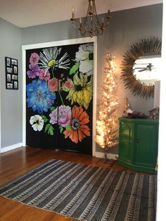 a decorated door with flowers painted on it in front of a green cabinet and christmas tree