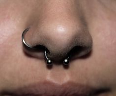 a nose piercing with two balls attached to the side of it's nose is seen in this close up photo