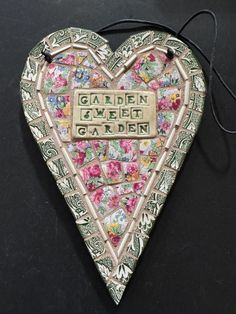 a decorative garden heart hanging on a black surface with the words garden written in it