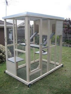 a large white bird cage sitting in the grass