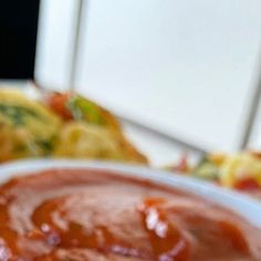 a bowl of sauce sitting on top of a white plate