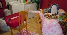 a messy kitchen and dining room with clothes strewn on the floor, including an old washing machine