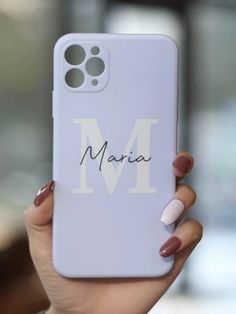 a woman holding up her phone case with the letter m on it