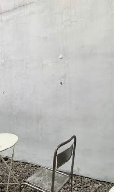 two chairs and a table sitting next to each other in front of a white wall