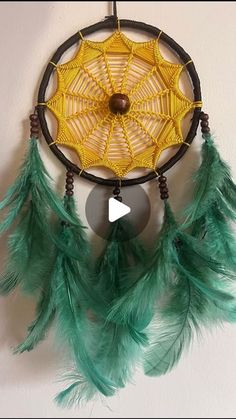 a yellow and green dream catcher hanging on the wall next to a black circle with an arrow