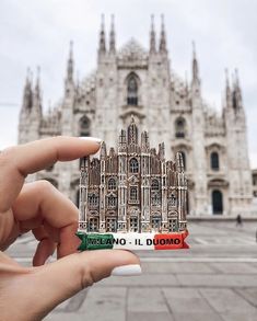 a person holding up a small sticker in front of a building that is made out of wood