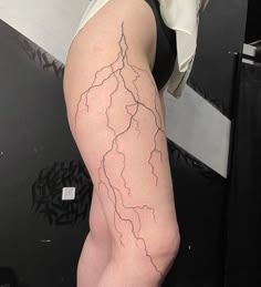 a woman's leg with a lightning tattoo on her left thigh and the lower half of her body visible