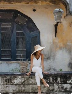 a woman sitting on the ledge of an old building