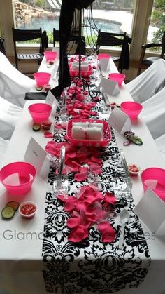 the table is decorated with pink and black flowers, napkins, and place settings