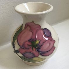 a white vase with pink flowers painted on it