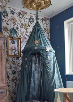 a canopy bed in the corner of a room with blue walls and floral wallpaper