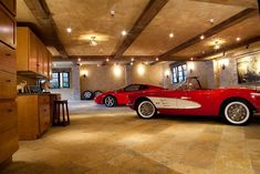 two red sports cars parked in a large room with lights on the ceiling and wood cabinets