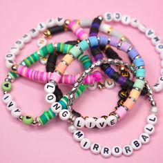 several bracelets with words on them sitting on a pink surface and the word love is spelled in small letters