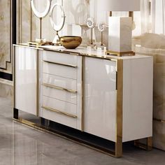 a white and gold sideboard with two mirrors on it's sides, next to a lamp