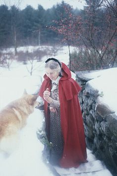 a woman standing next to a dog in the snow