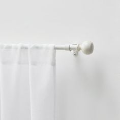 a white curtain hanging on the side of a window with an eyelet in front of it