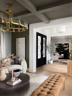 a living room filled with furniture and a chandelier hanging from the ceiling above