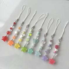 six different colored stars are hanging from silver earwires on a white table top