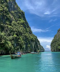 several boats floating on the water in front of some mountains and trees with blue sky