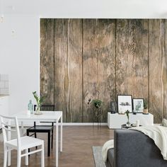 a living room filled with furniture next to a wall covered in wood planks and white chairs