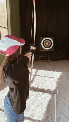 a woman is practicing her archery skills in the snow, with an arrow and target behind her