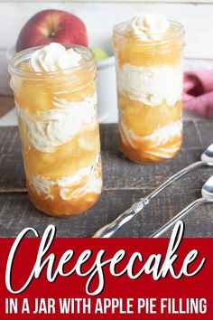 two jars filled with cheesecake in front of an apple and spoons on a table