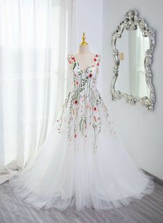 a white dress on display in front of a mirror and window with curtains behind it