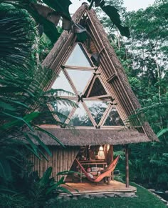 a house made out of wood and grass with a hammock hanging from the roof