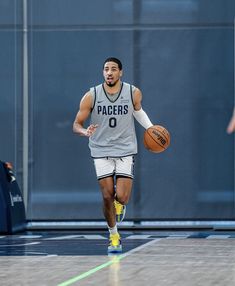 a man dribbling a basketball on the court with another person in the background