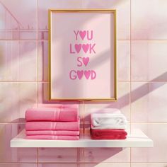 a bathroom with pink tiles and towels on the shelf in front of it is a framed print that says you love my son god