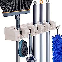 a broom, brush and other cleaning supplies are hanging on a rack in front of a white background