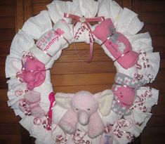 a baby wreath is decorated with pink and white items, such as a stuffed elephant